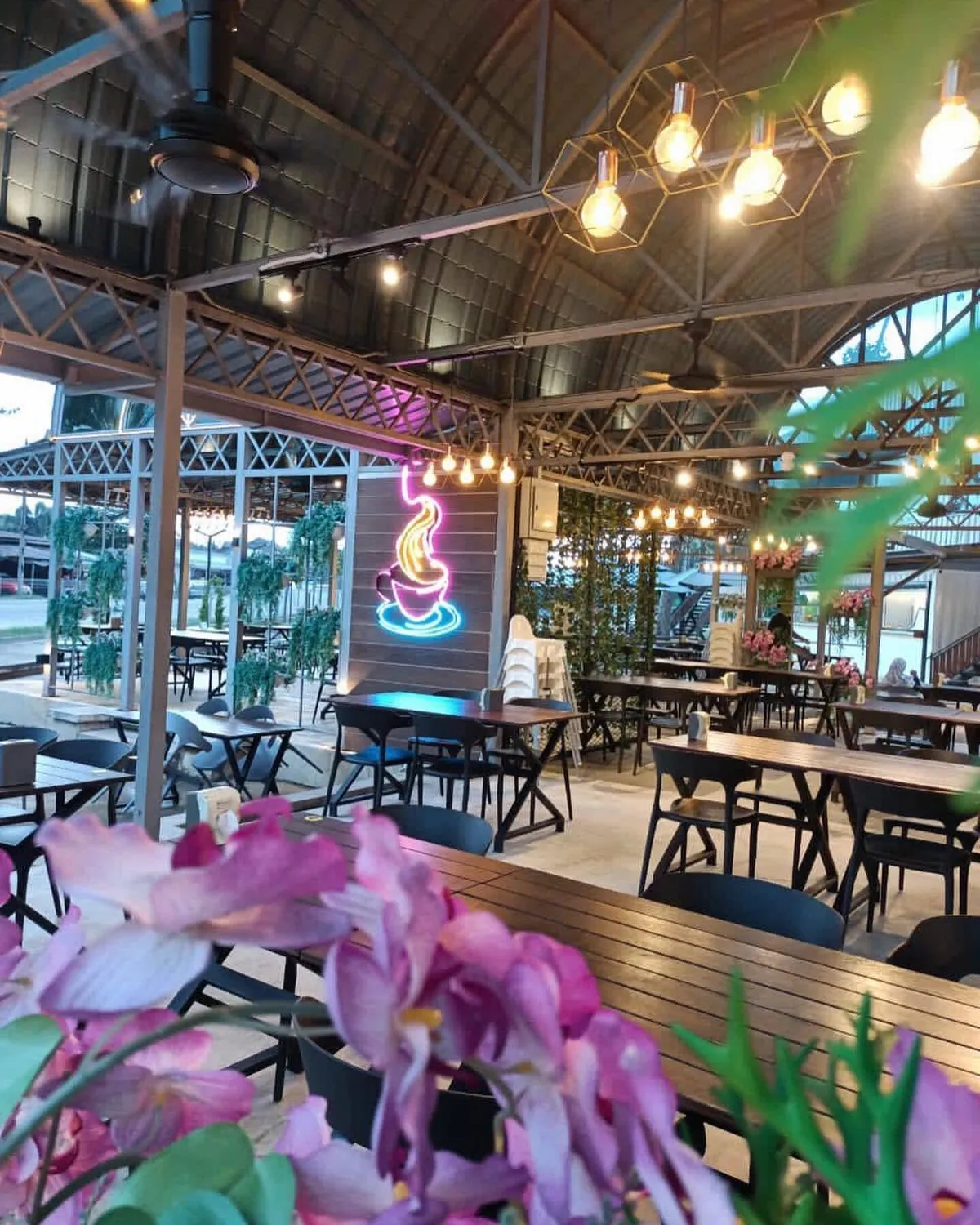 Pandangan luas ruang makan terbuka Laman Café dengan bumbung zink, kekuda besi dan deretan mentol kuning.